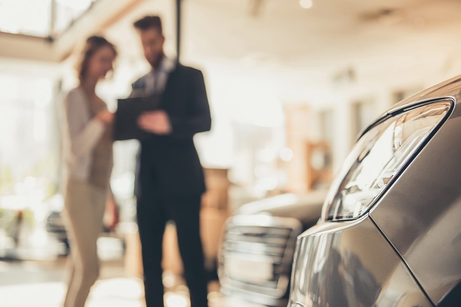 专业商业保险-妇女购买新车后在汽车陈列室查看保险细节