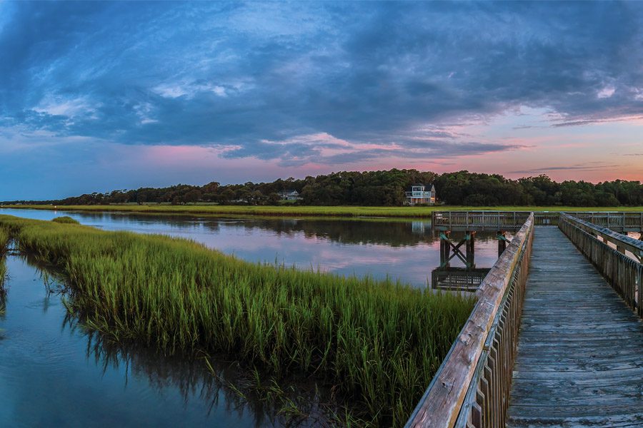 Wagener SC Insurance - View From An Old Bridge Leading Out Into The Purple and Pink Sky Over A Green Marsh At Dusk